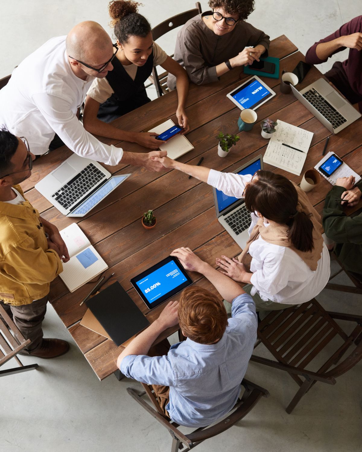 A groupd of pople sitting around a work table with computers and tablets.